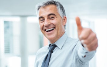 mediation_352x220_2023_07 Fröhlicher Geschäftsmann, der lächelnd einen Daumen nach oben streckt