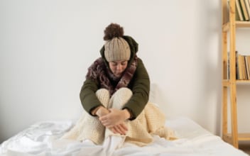 mietminderung_352x220_2023_04 Frau sitzt frierend mit Mütze und Winterjacke in ihrer Wohnung