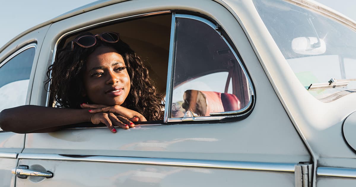 Junge Frau blickt aus einem Oldtimerauto